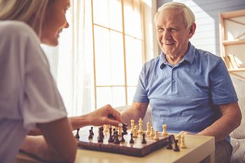 Pflegekraft und älterer Mann spielen Schach